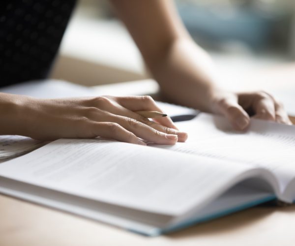 Student preparing for college test, exam, reading book Student preparing for college test, exam, reading book, studying textbook, writing notes, making summary for class report. Learning workplace table, hands with pencil close up